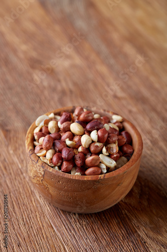 Two ceramic bowls with raw peanuts mix isolated over rustic wooden backround, top view, close-up.