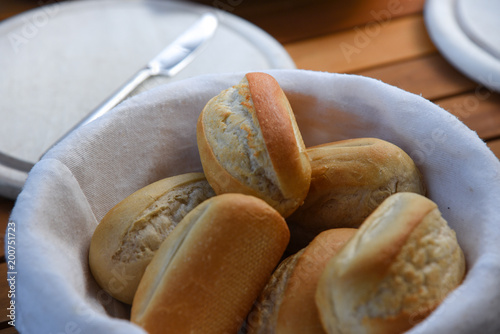 Basket of freshly baked dinner rolls with tableware in background. Macro photo