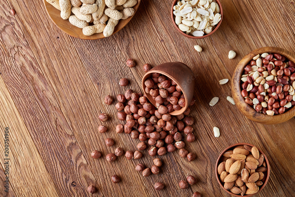 A composition from different varieties of nuts in a wooden bowls on rustic background, close-up, shallow depth of field A composition from different varieties of nuts in a wooden bowls on rustic background, close-up, shallow depth of field