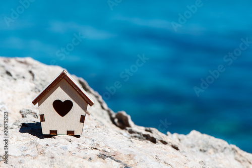 Small house on a stone on the background of the blue sea, space for text, the concept of a house by the sea, a summer holiday, life by the sea