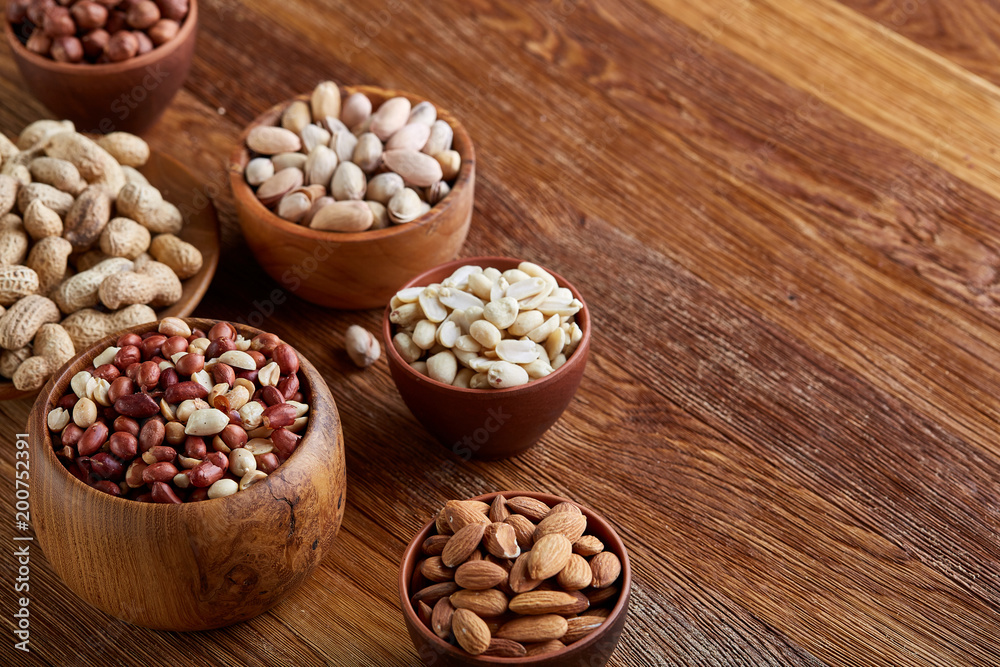 A composition from different varieties of nuts in a wooden bowls on rustic background, close-up, shallow depth of field