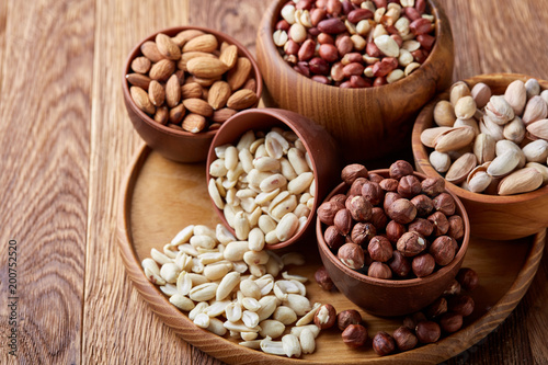 A composition from different varieties of nuts in a wooden bowls on rustic background, close-up, shallow depth of field