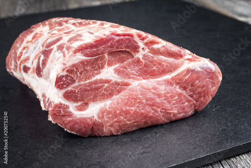 Row piece of Bosten butt pork offered as close-up on a black board