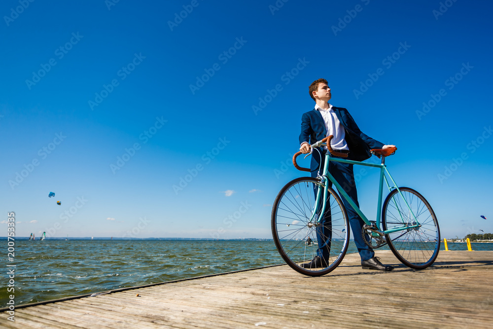 Young man standing with bike on pier