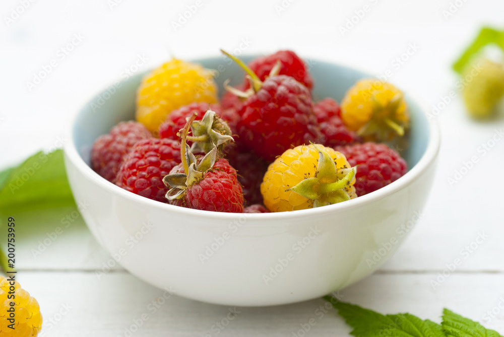 red and rare yellow raspberry fruits on white wooden table background red and rare yellow raspberry fruits on white wooden table background