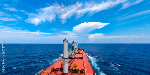 Indian ocean. Cargo ship moving towards skyline and beautiful clouds in calm sea
