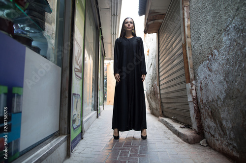 Beautiful woman in abaya walking through the streets of the old city. © kanashkin
