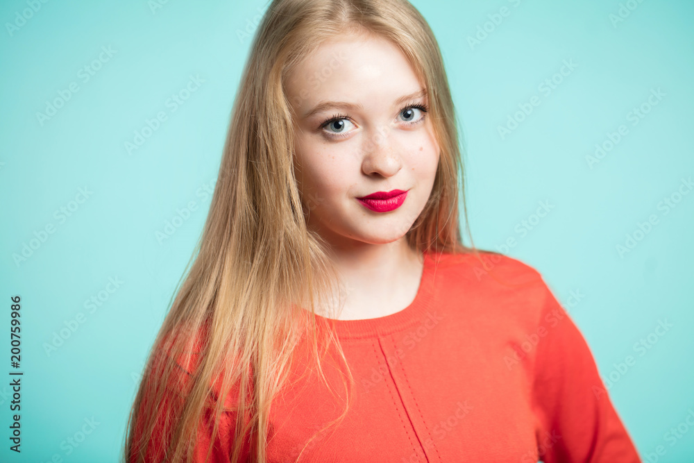 Portrait of beautiful young woman with red lips on blue background. Blonde girl looking at the camera Portrait of beautiful young woman with red lips on blue background. Blonde girl looking at the camera