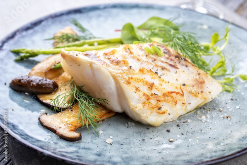 Photography Fried cod fish filet with green asparagus and mushrooms as close up on a plate