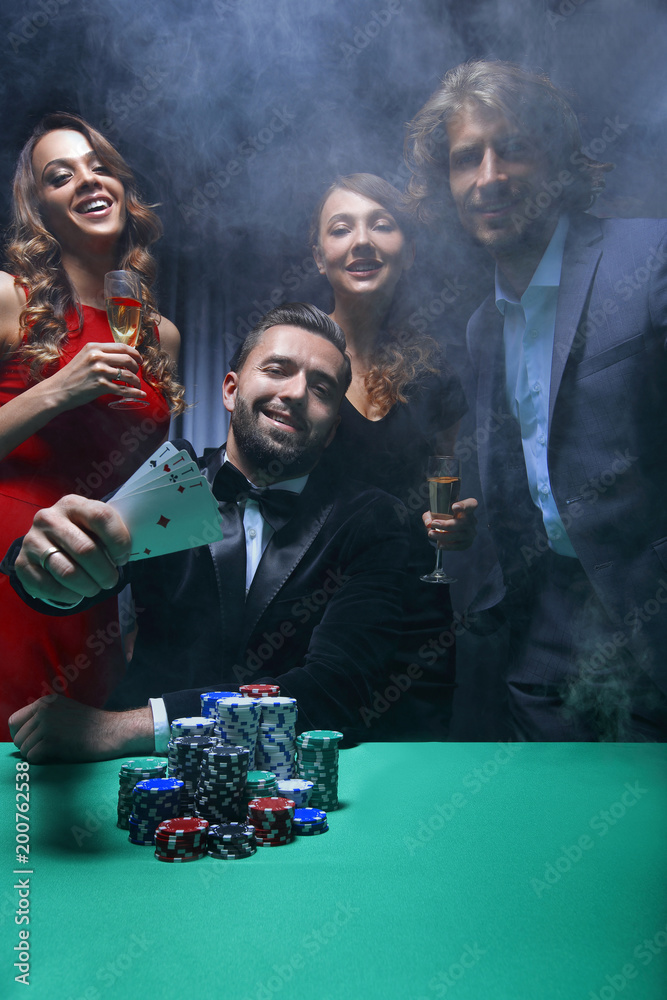 portrait of group of people with drinks playing poker in casino portrait of group of people with drinks playing poker in casino