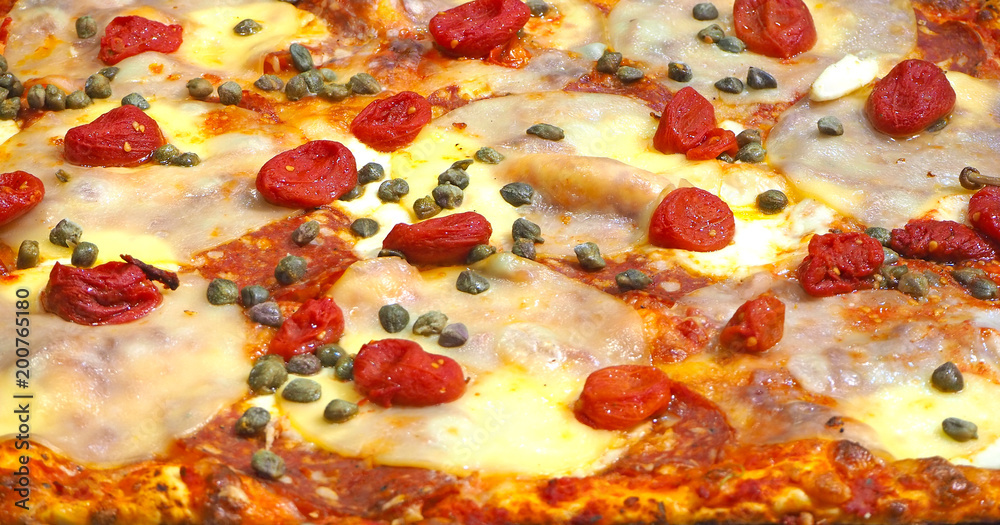 Delicious Italian pizza with capers and tomatoes, cooked in the wood oven