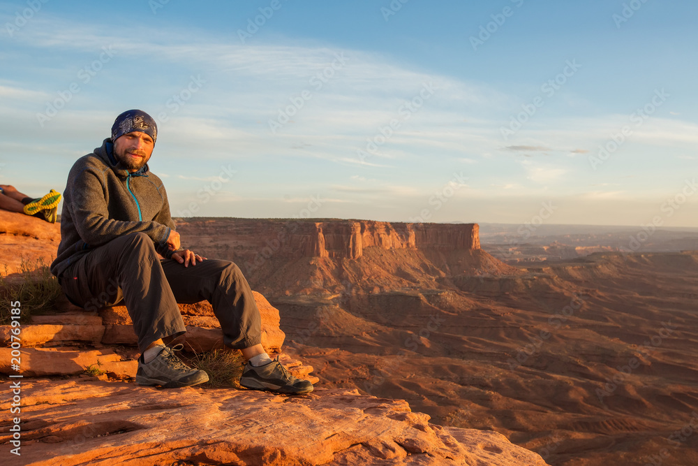Hiker meets sunset at Grand view point in Canyonlands National park in Utah, USA