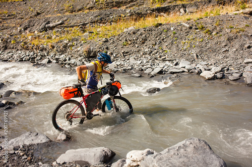 Mountain biker is crossing the river in the highlands of Tusheti region, Georgia