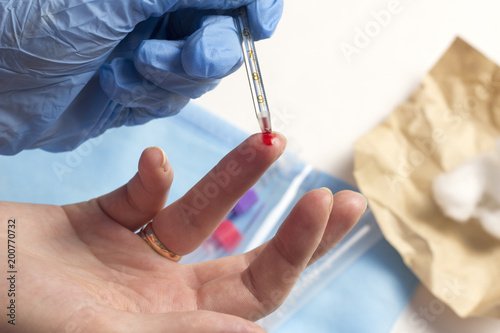 A doctor takes blood from a finger  close-up