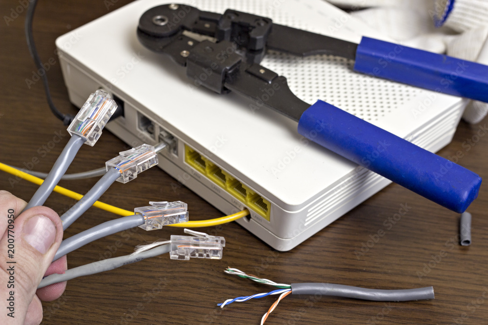 A man holds a network cable in his hand, a modem on the desk, a close-up A man holds a network cable in his hand, a modem on the desk, a close-up