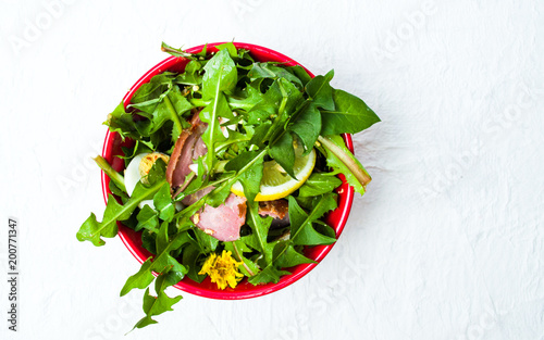 Dandelion salad with eggs meat and lemon in a bowl