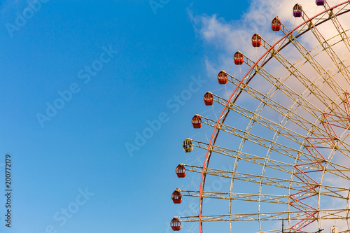 Giant ferris wheel against blue sky and white cloud which mean an amusement-park, close up photo