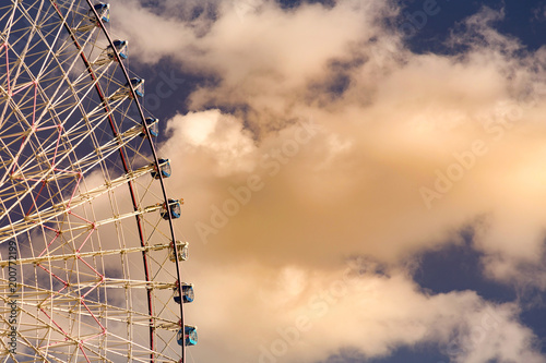 Path of gaint ferris wheel aginst white clouds over blue sky photo