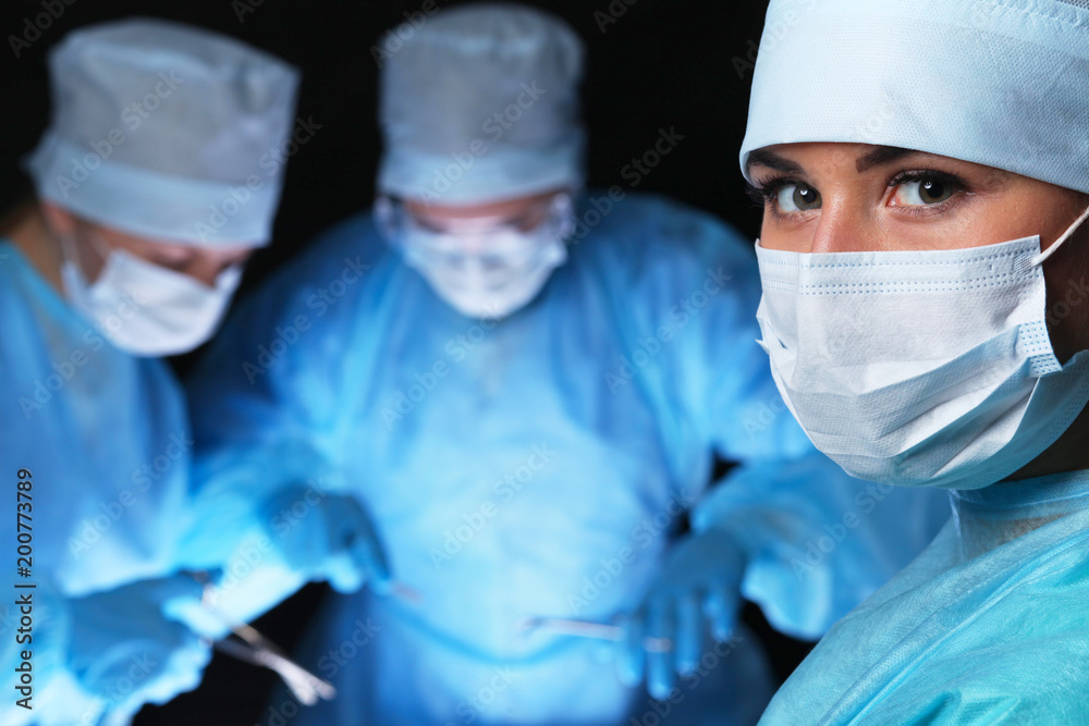 Closeup of surgeons performing operation. Focus on female nurse. Medicine, surgery and emergency help concepts Closeup of surgeons performing operation. Focus on female nurse. Medicine, surgery and emergency help concepts
