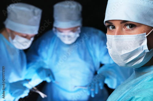 Fototapeta Naklejka Na Ścianę i Meble -  Closeup of surgeons performing operation. Focus on female nurse. Medicine, surgery and emergency help concepts