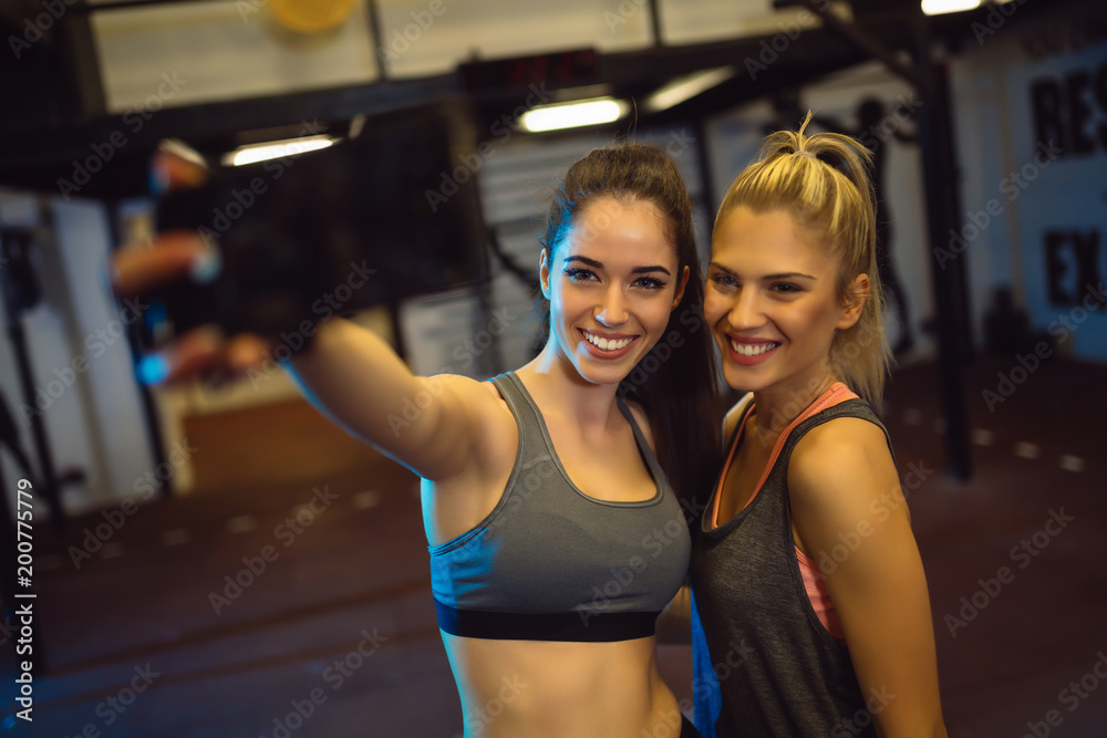 Two good looking girls are taking selfie in the gym Two good looking girls are taking selfie in the gym