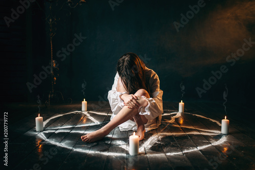 Female person sitting in pentagram circle, magic photo