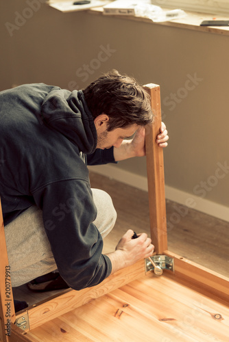 Canvas Print man screws the legs to a wooden table