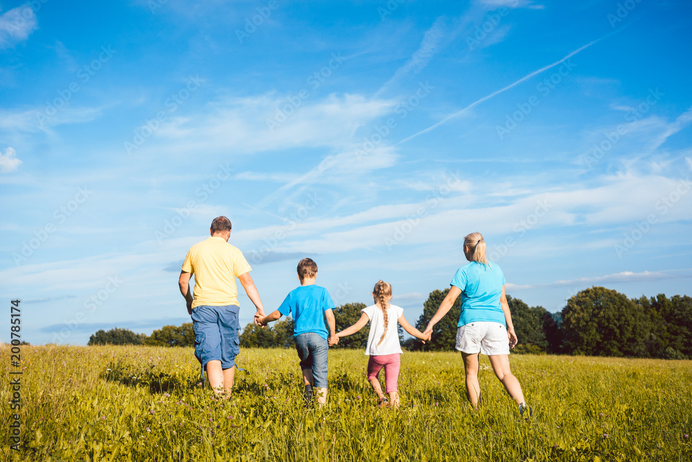 Family holding hands running over meadow, mother, father and children Family holding hands running over meadow, mother, father and children