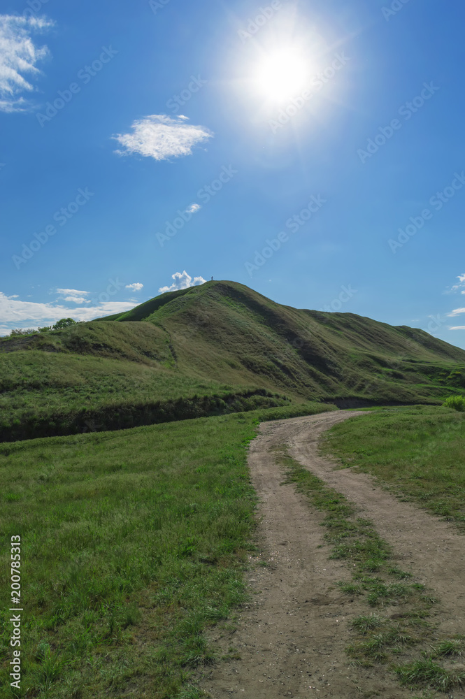 Fototapeta premium a dirt road leading to a hill