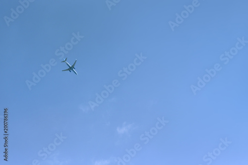 Passenger plane flies high against a blue sky background