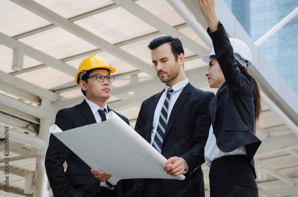 group of business or engineer woman and man with safety helmet and blueprint planning at the building and checking their work in modern city, planning start up new project, successful concept group of business or engineer woman and man with safety helmet and blueprint planning at the building and checking their work in modern city, planning start up new project, successful concept