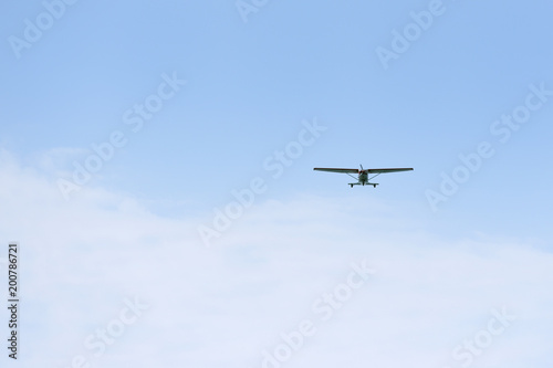 Light propeller aircraft comes to land on a blue sky background