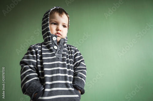 Foto Sad cute small boy holding hands in pullover pockets