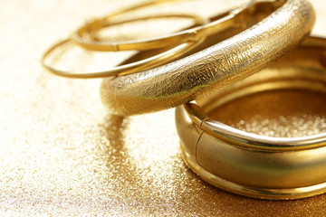 gold jewelry bracelets on gold background