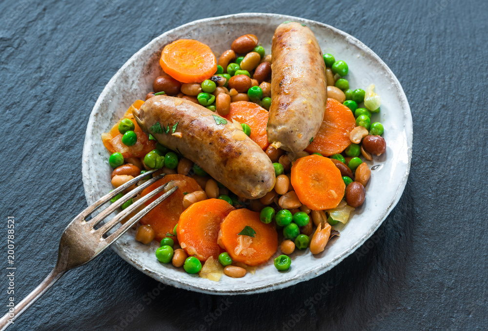 Sausage and bean casserole with carrots and green peas - top view