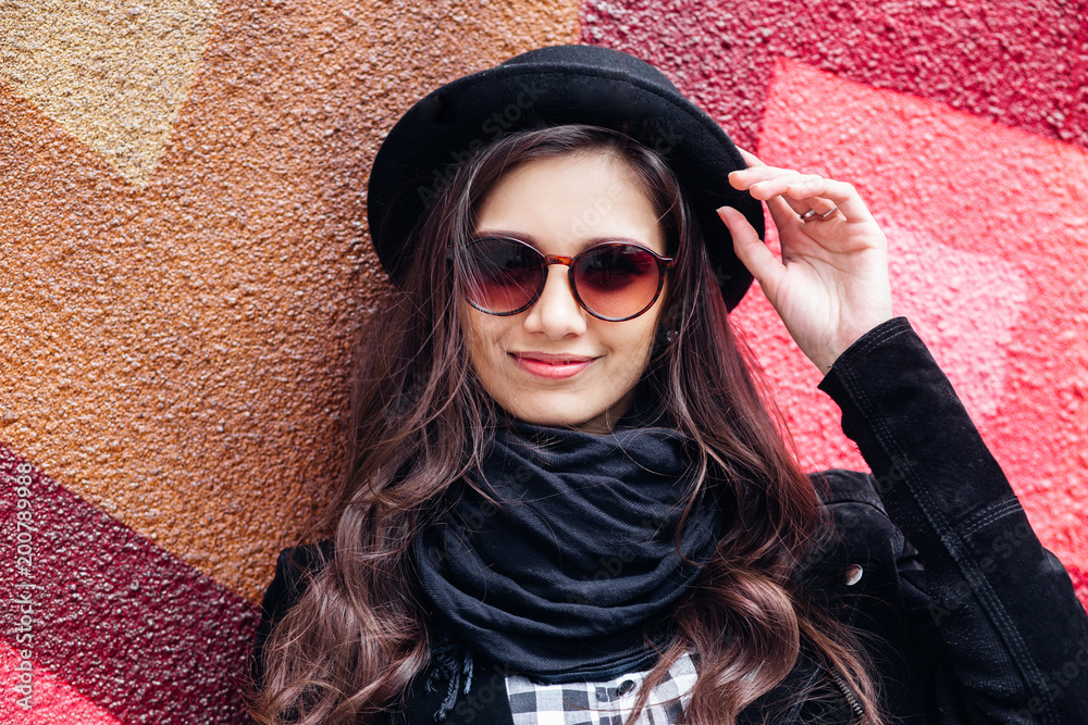 Smiling urban girl with smile on her face. Portrait of fashionable gir wearing a rock black style having fun outdoors in the city street Smiling urban girl with smile on her face. Portrait of fashionable gir wearing a rock black style having fun outdoors in the city street