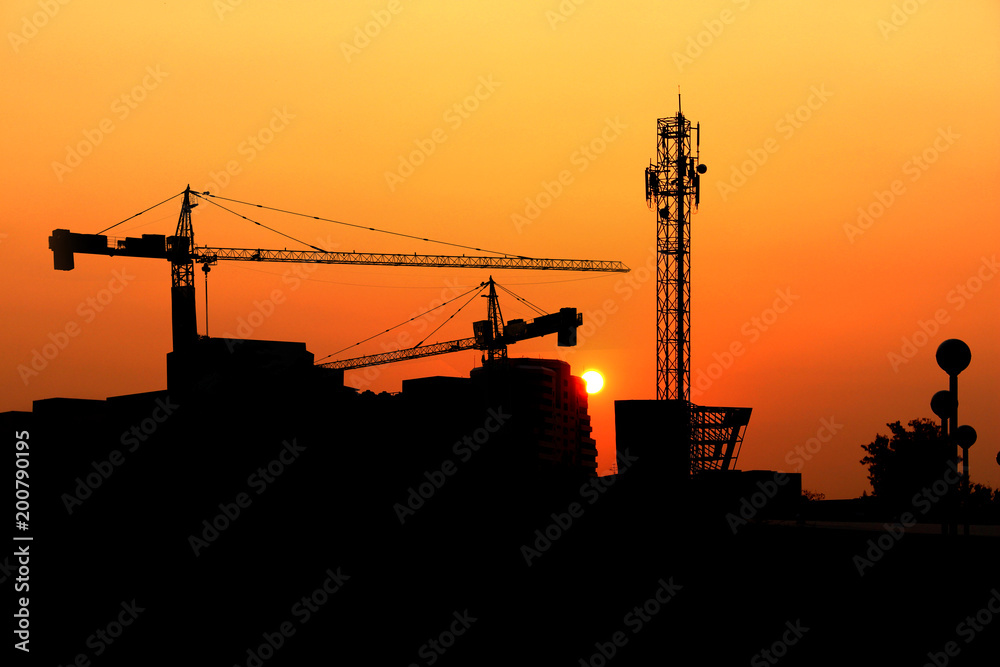Silhouette crane construction building at sunset