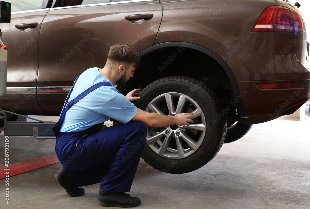 Mechanic changing car wheel in garage. Tire service Mechanic changing car wheel in garage. Tire service