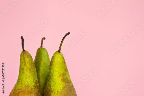 upper part of three long ripe pears on a trendy pink background
