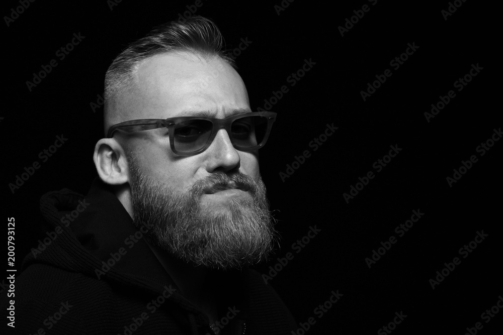 portrait of a brutal man close-up on a black background wearing glasses portrait of a brutal man close-up on a black background wearing glasses