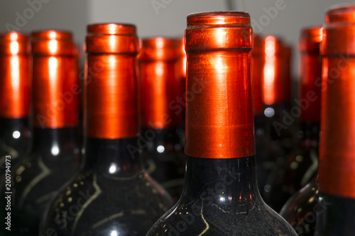 фотографія dusty necks of wine bottles with beautiful shiny bright red capsules (foil) clos