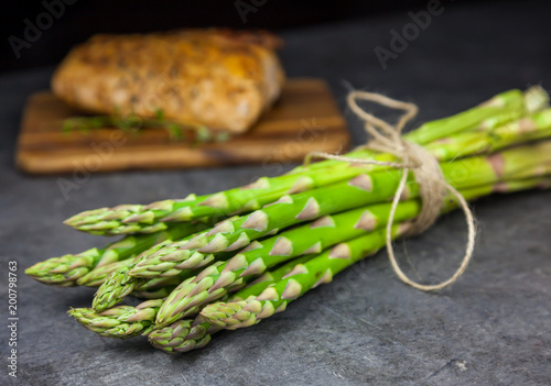 A bunch of asparagus with roasted pork tenderloin on the grey background