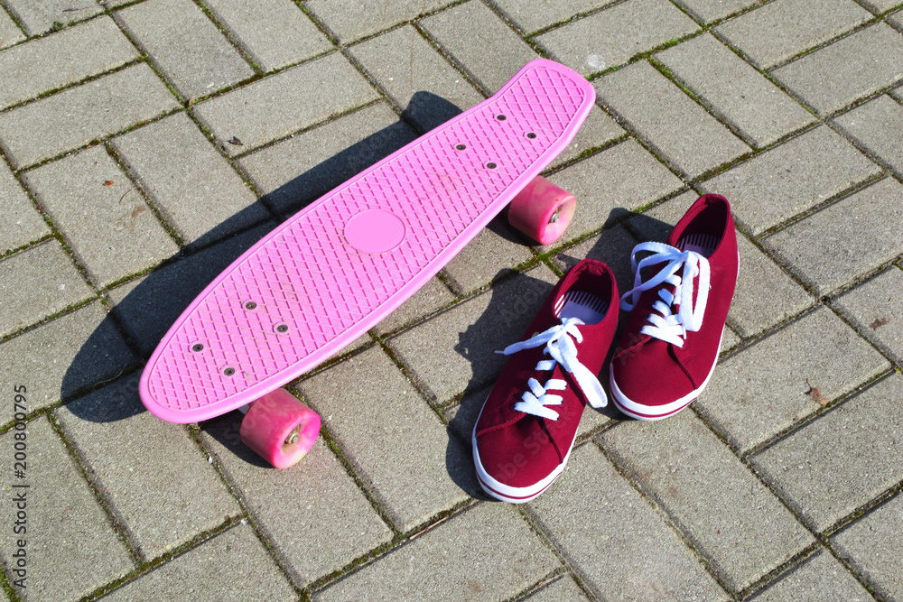 Pink penny board and red sport shoes on grey pavement background outdoors.  Stock Photo | Adobe Stock