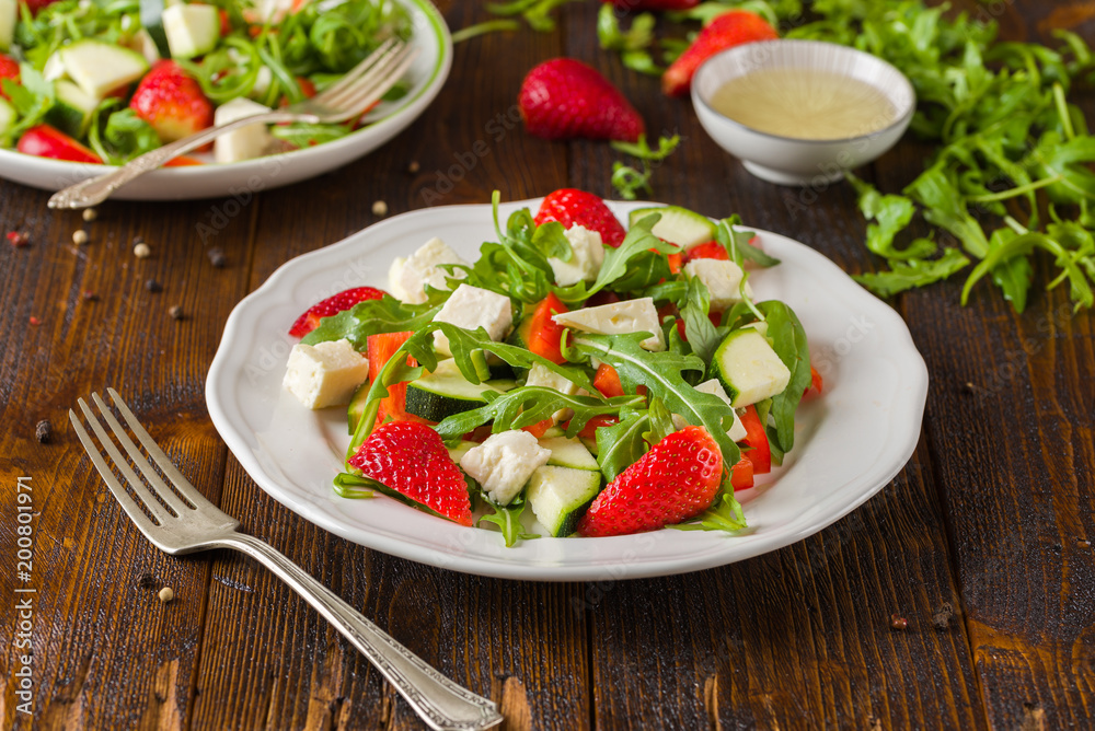 Fresh vegetable strawberry salad on white plate on natural rustic desk. Fresh vegetable strawberry salad on white plate on natural rustic desk.