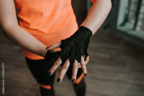 Close-up image of female hand with black strap. Preparing for boxing.