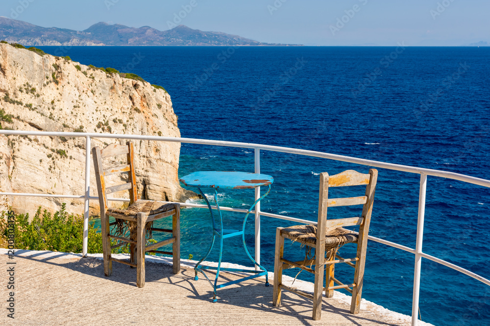 Table with chairs on terrace overlooking blue sea in summer day. Zakynthos, Greece