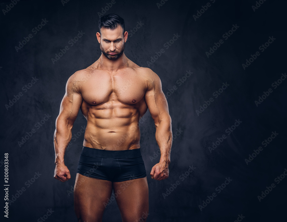 Portrait of a shirtless tall huge male with a muscular body with a stylish  haircut and beard, in a underwear, posing in a studio. Photos | Adobe Stock