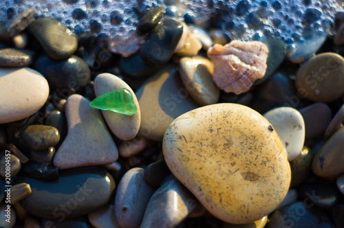 pebble stones on the sea beach, the rolling waves of the sea with foam