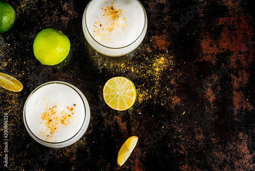 Peruvian, Mexican, Chilean traditional drink pisco sour liqueur, with fresh lime, on rusty black table, copy space top view photo