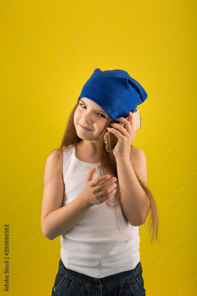 Beautiful caucasian girl posing on yellow isolated background in studio holding in hands mobile phone